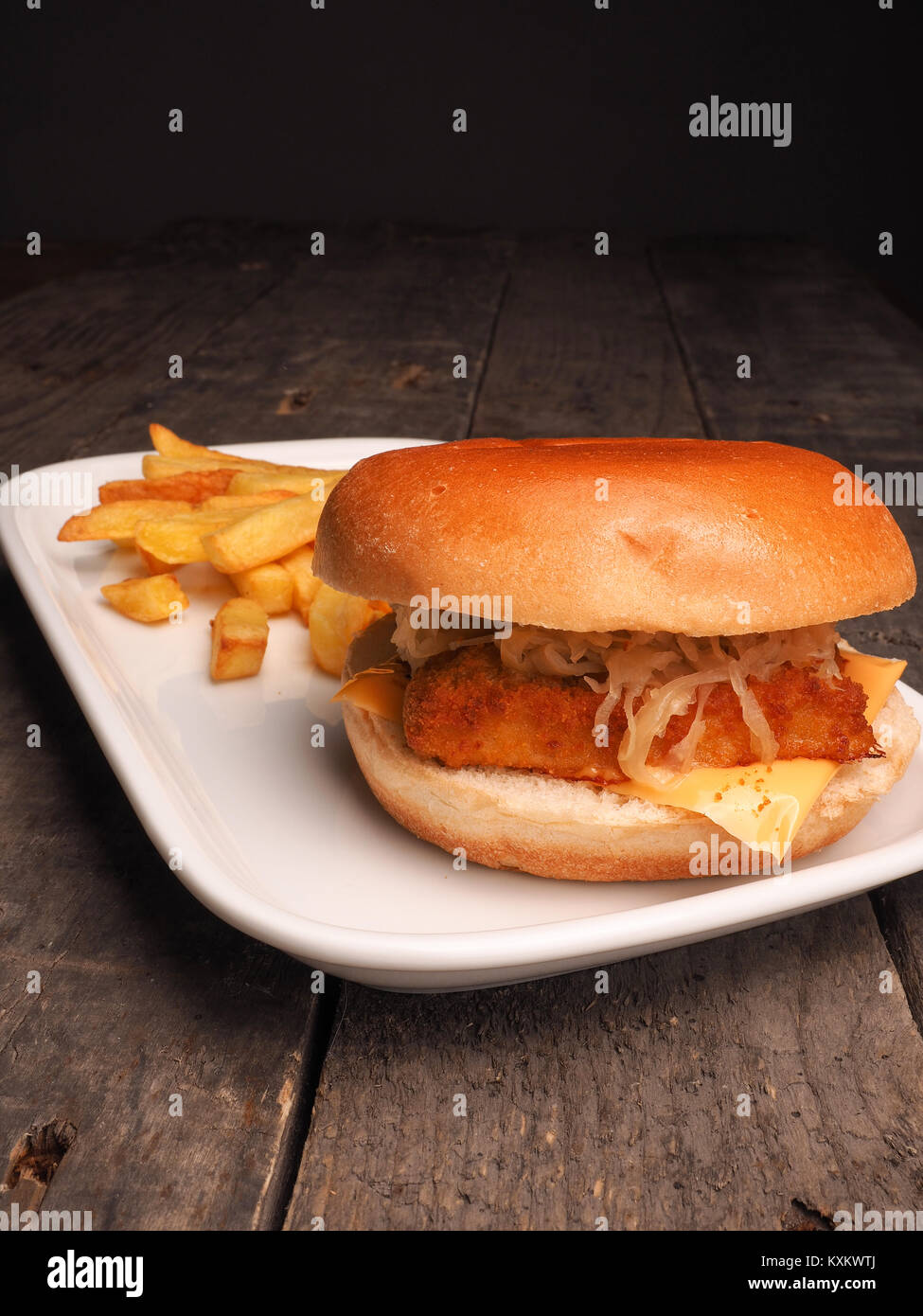 Hamburger di pesce con patatine fritte su una piastra bianca Foto Stock