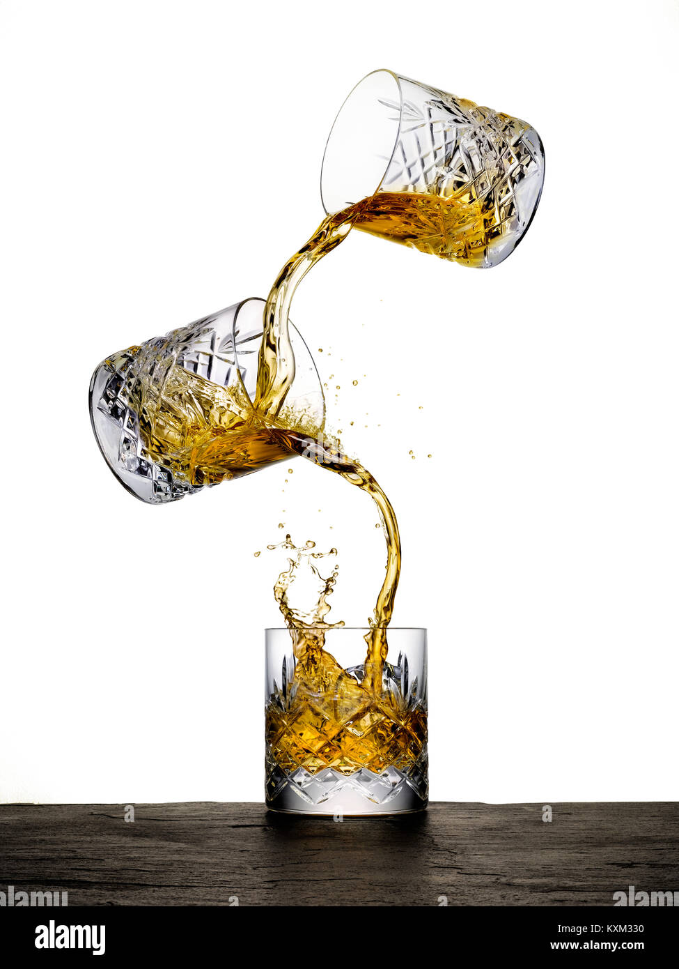 Due bicchieri di whiskey tumbling e miscelazione in un terzo vetro. Foto Stock
