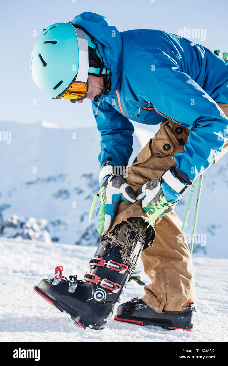 Uomo maturo indossando skiwear,mettendo su scarponi da sci Foto Stock