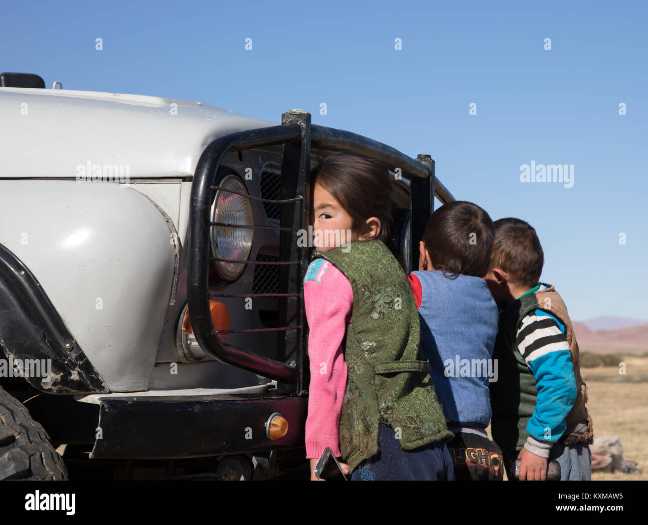 Paese rurale di lato i bambini giocando con auto bambina guardando sopra la sua spalla in Mongolia Foto Stock