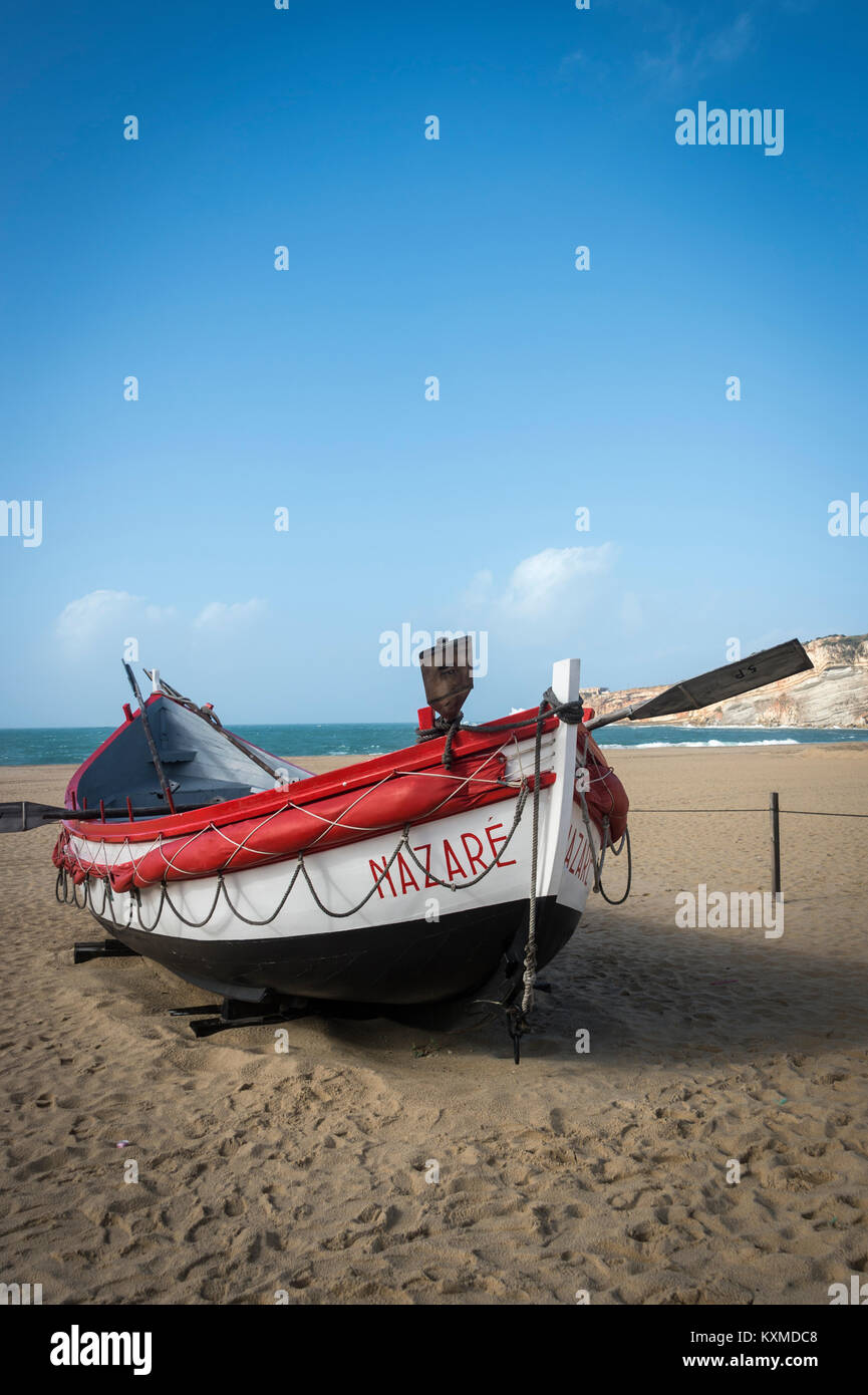 Tradizionale in rosso e bianco verniciato scialuppa di salvataggio sulla spiaggia a Nazare, Portogallo. Foto Stock