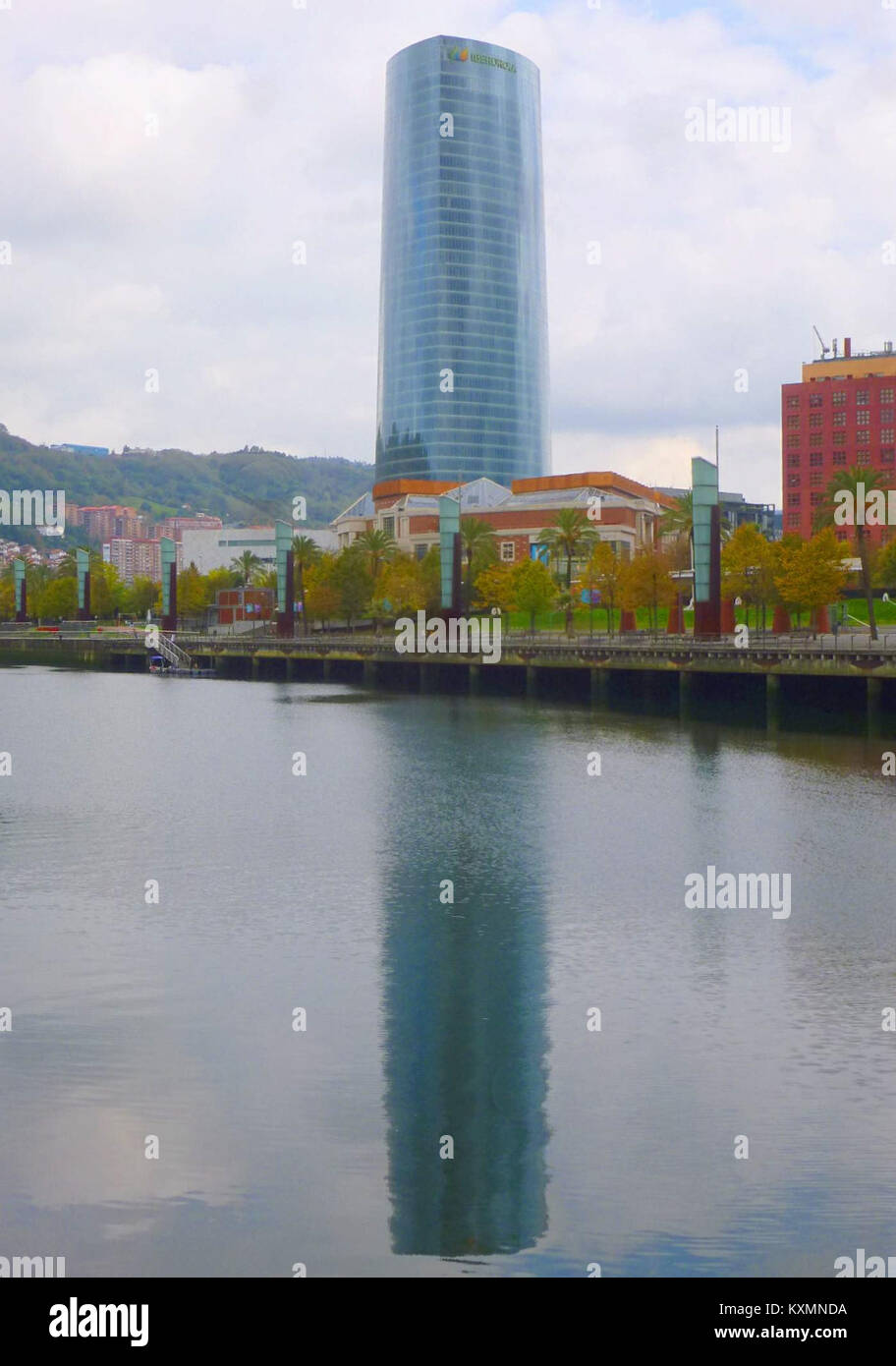 Questa immagine presenta la Torre Iberdrola di Bilbao, un iconico grattacielo situato lungo il Ría de Bilbao, che mostra l'architettura moderna e lo sviluppo urbano della città. Foto Stock