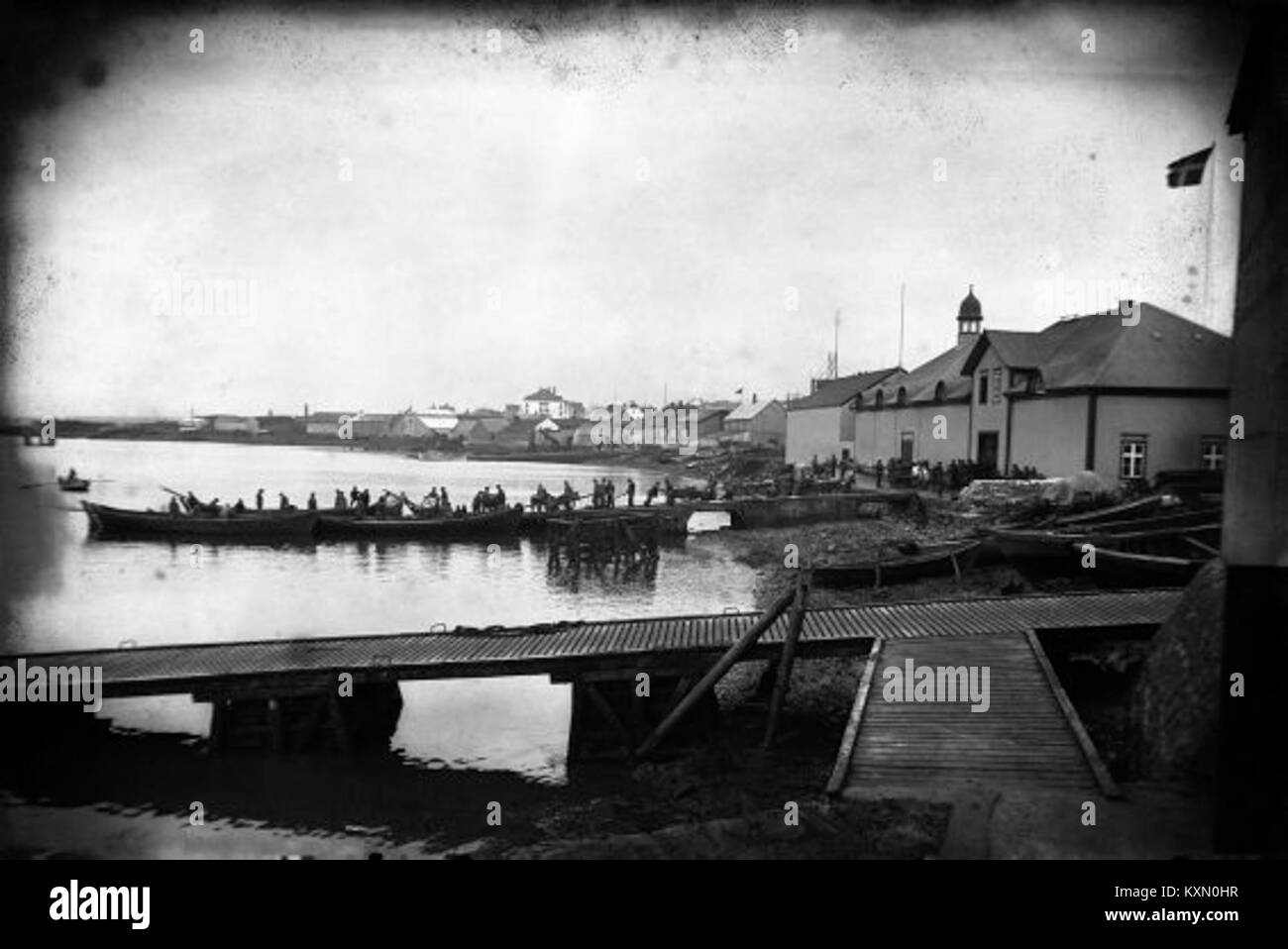 Questa immagine raffigura la vita serale al porto di Reykjavik in Islanda tra il 1910 e il 1914, mostrando le attività marittime, la cultura locale e le infrastrutture portuali del periodo. Foto Stock