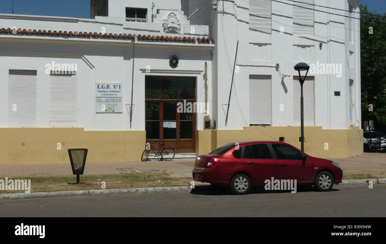 Fotografia di Escuela EGB 1 ad América, una città in Argentina, che mostra l'edificio scolastico e la sua posizione di fronte alla piazza centrale. Foto Stock