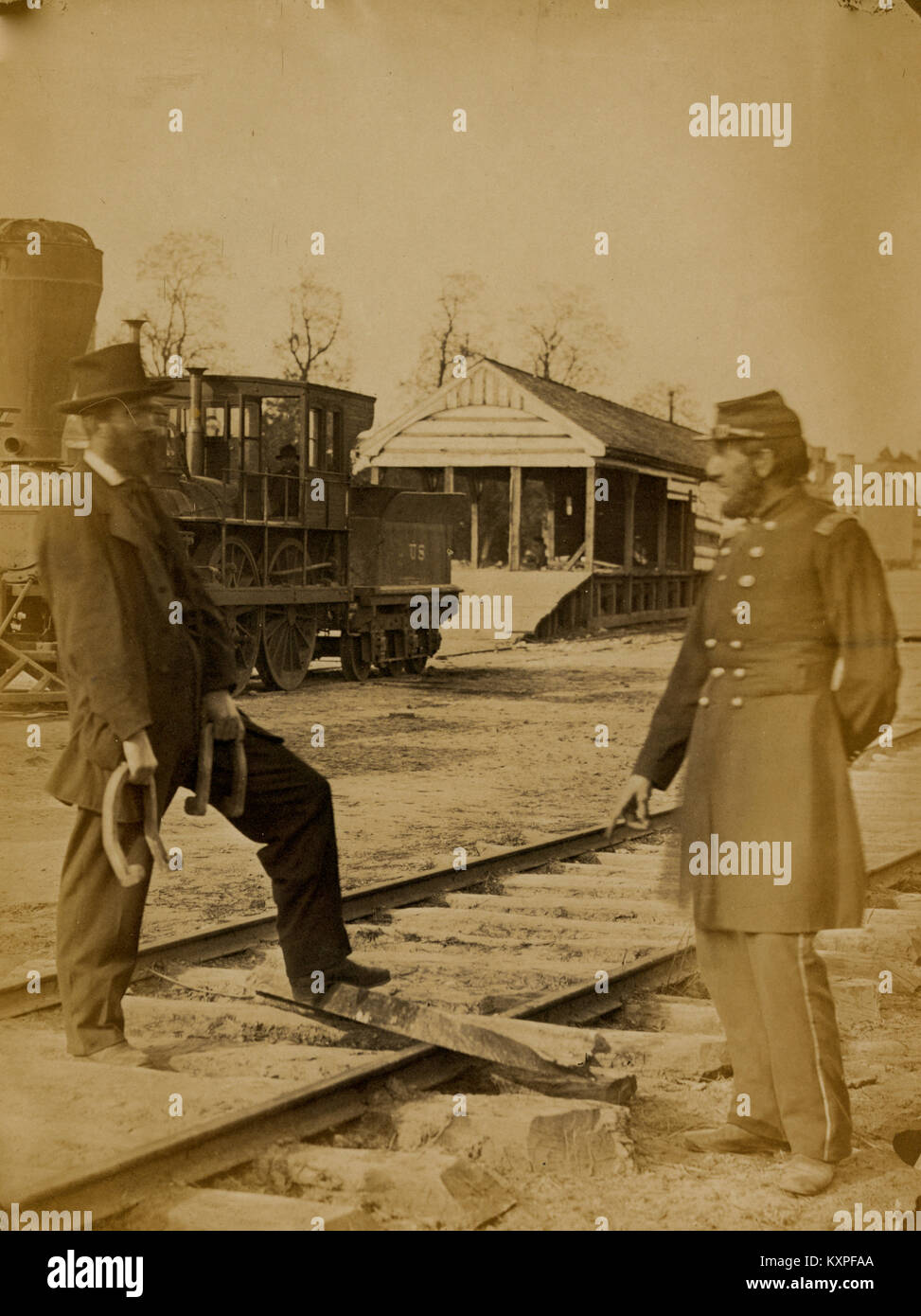 Soldato e un altro uomo in piedi presso i binari della ferrovia nella parte anteriore del locomotore Foto Stock