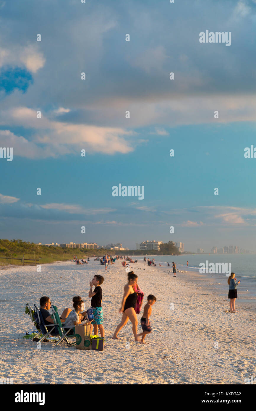 Famiglia godersi il tramonto su un inverno di sera, spiaggia a piedi nudi, Naples, Florida, Stati Uniti d'America Foto Stock