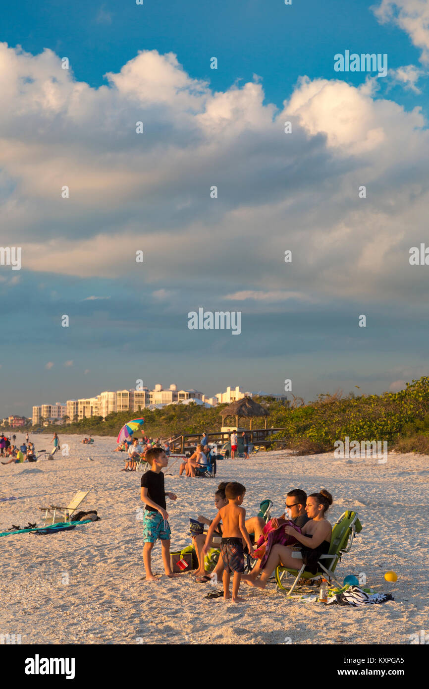 Famiglia godersi il tramonto su un inverno di sera, spiaggia a piedi nudi, Naples, Florida, Stati Uniti d'America Foto Stock
