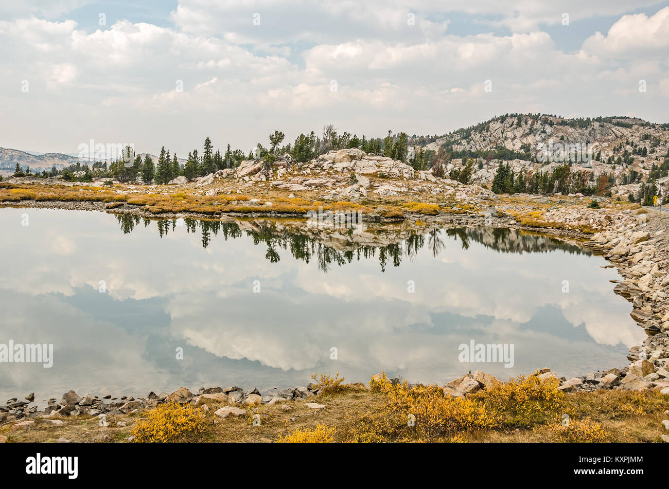 Calmo lago di montagna con belle Nuvole e riflessi e un po' di foschia nelle montagne distanti Foto Stock