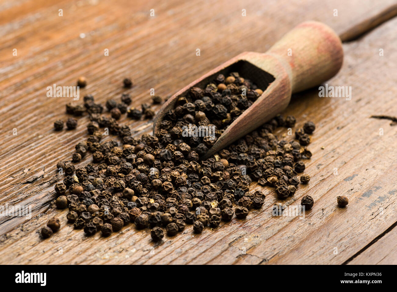 Cucchiaio di legno con peppe nero sul tavolo Foto Stock