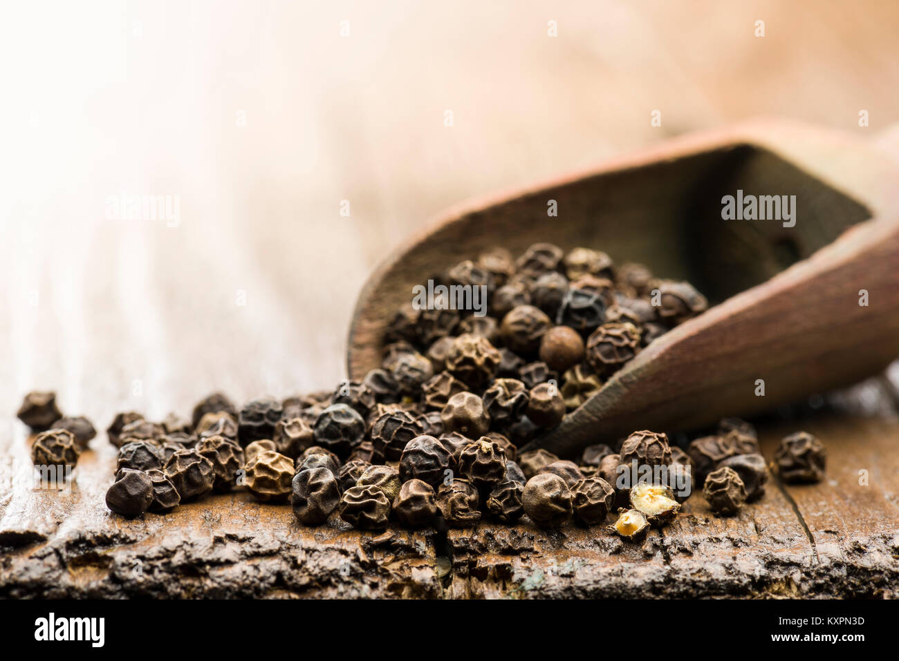 Cucchiaio di legno con peppe nero sul tavolo Foto Stock