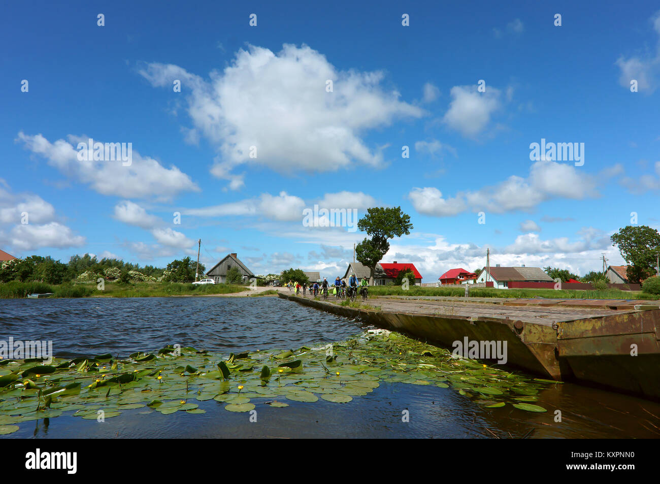 Bel posto, un pontone ponte che attraversa il fiume, un gruppo di ciclisti in viaggio sul ponte del villaggio fuori città in estate Foto Stock