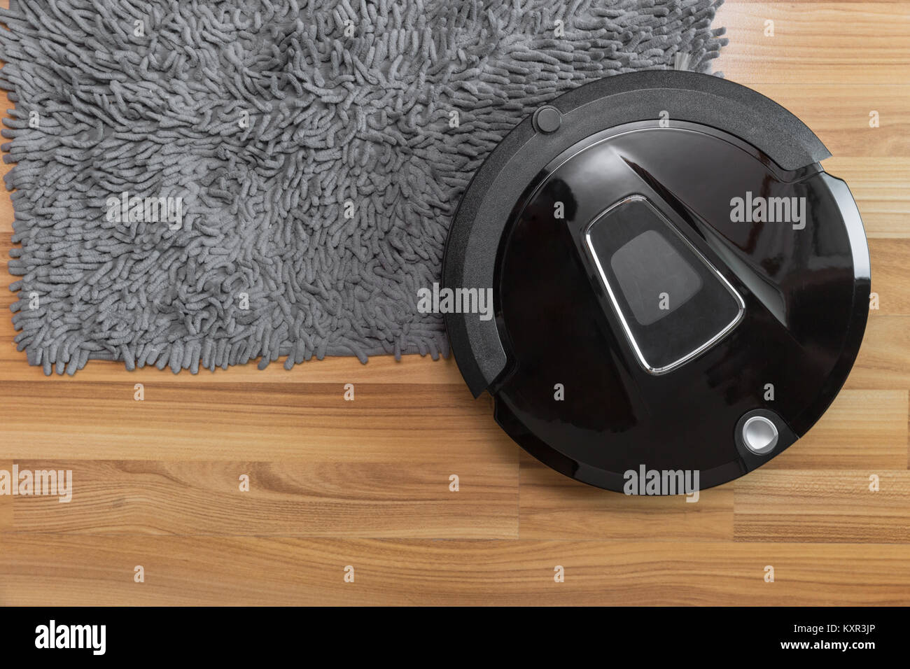 Robot aspirapolvere sul laminato pavimento in legno con pulizia moquette Foto Stock