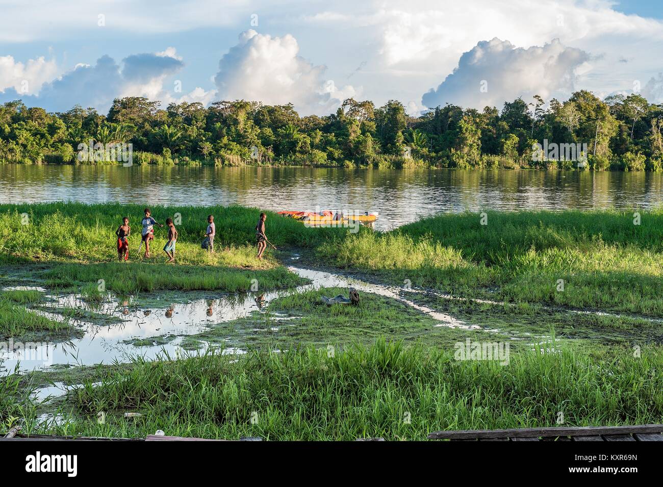 Sconosciuto i bambini giocano sulla riva del fiume vicino al villaggio. Declino e fine del giorno. Giugno 26, 2012 nel villaggio, Nuova Guinea, Indonesia Foto Stock