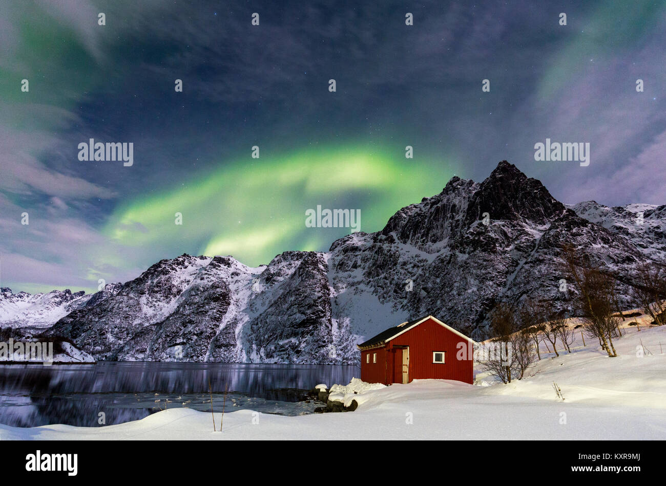 Lofoten, Svolvaer, Aurora Boreale su un lago ghiacciato e rosso rorbu, Norvegia. Foto Stock