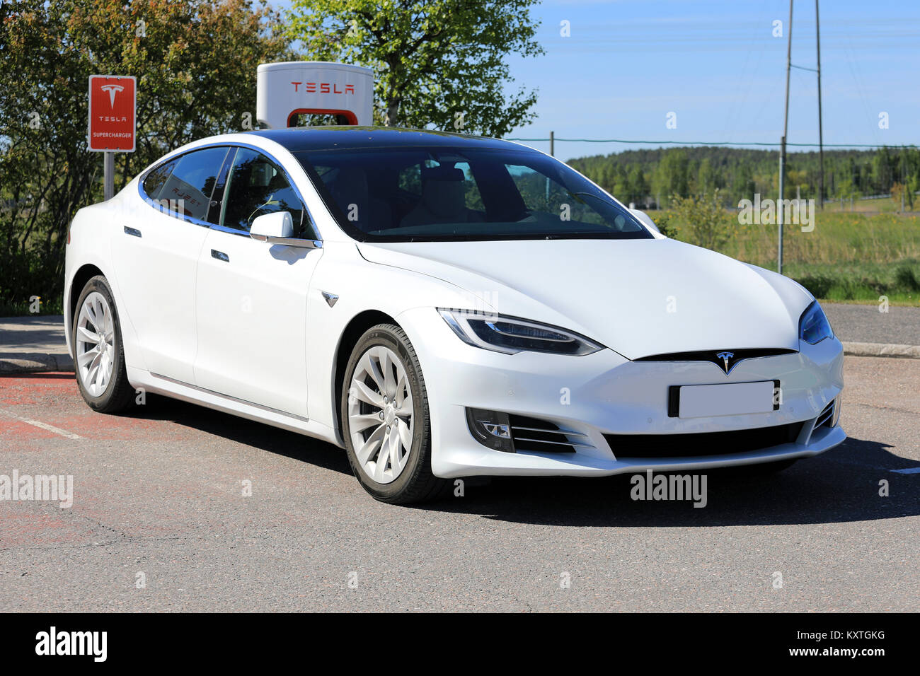 PAIMIO, Finlandia - 3 giugno 2017: Bianco Tesla Model S berlina di lusso con nuovo design all'esterno del veicolo è in carica di Tesla Supercharger Statio Foto Stock