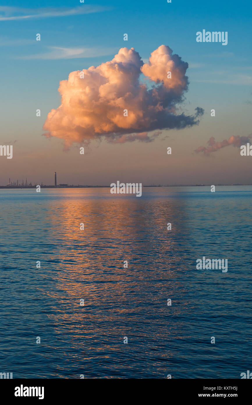 Cloud unico che riflette il bagliore rosso del tramonto. Il cloud è anche riflessa nella Solent, a Ryde, Isle of Wight, con una vista in lontananza Fawley Foto Stock