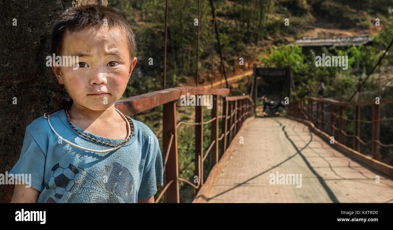 Yong boy appartenenti a sapa village in piedi vicino a ponte sospeso, Vietnam Foto Stock
