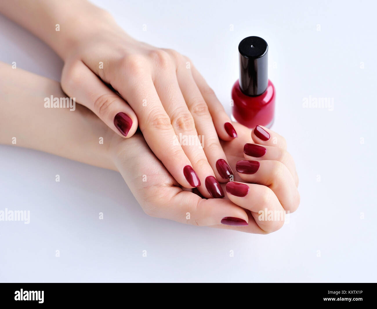 Le mani di una donna con il rosso scuro manicure e smalto per unghie bottiglia Foto Stock