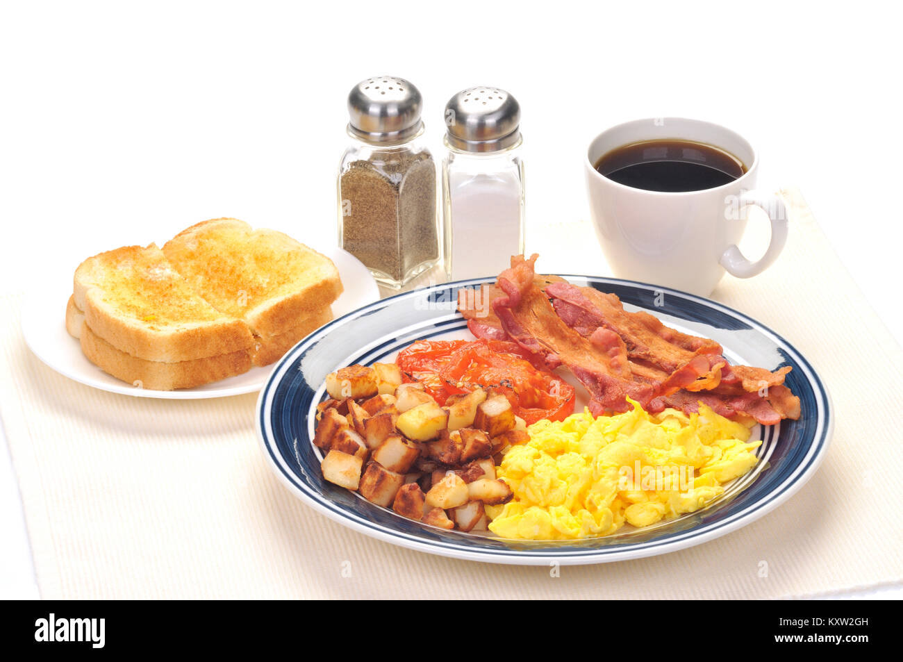 Piastra blu prima colazione speciale con uova strapazzate, hash brown patate, strisce di bacon, pomodoro grigliate, imburrato toast bianchi, una tazza di caffè nero Foto Stock