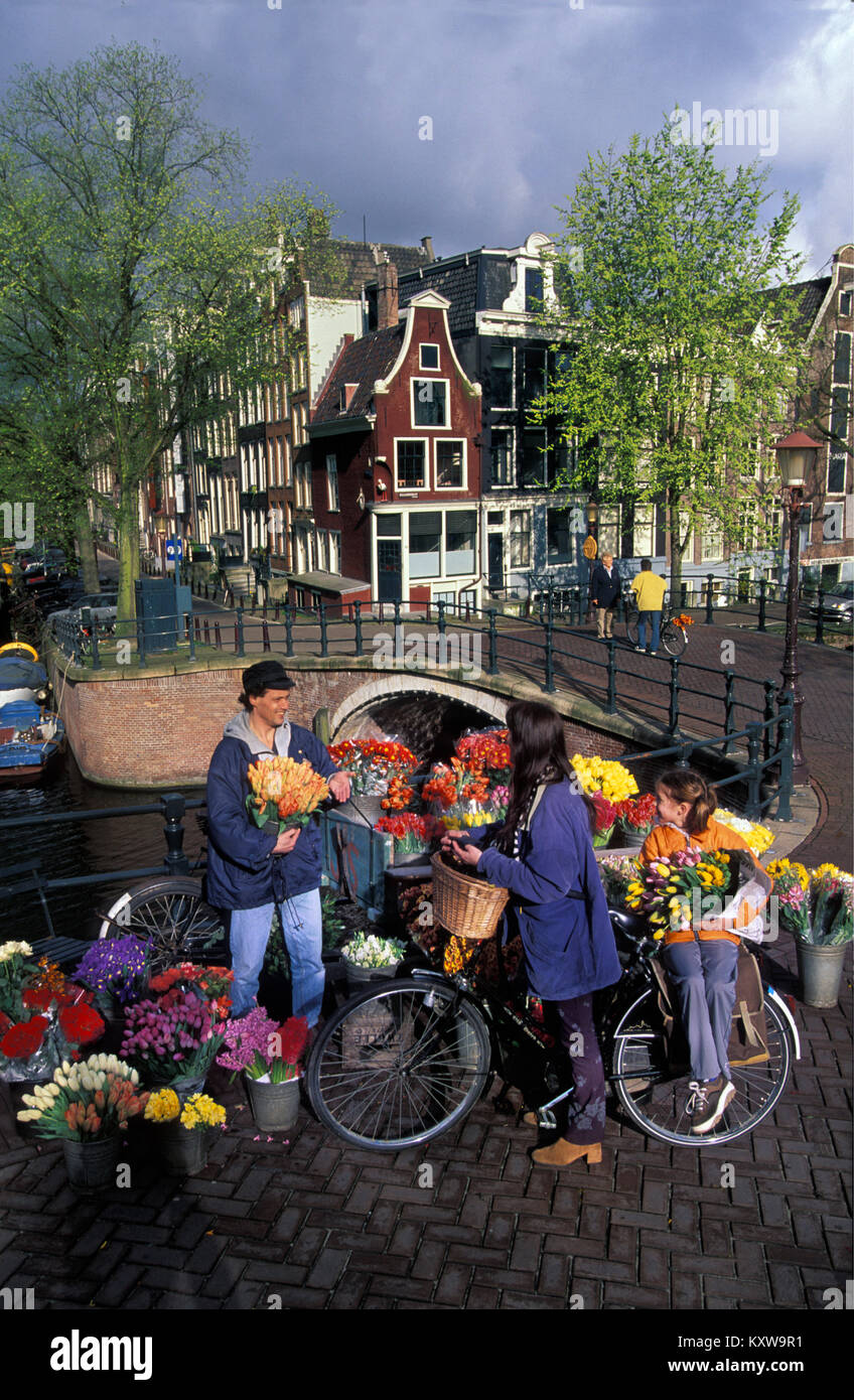 I Paesi Bassi, Amsterdam, sito patrimonio mondiale dell'UNESCO. Uomo che vendono fiori vicino al Canal. Golden Age case. Il XVII secolo. Foto Stock