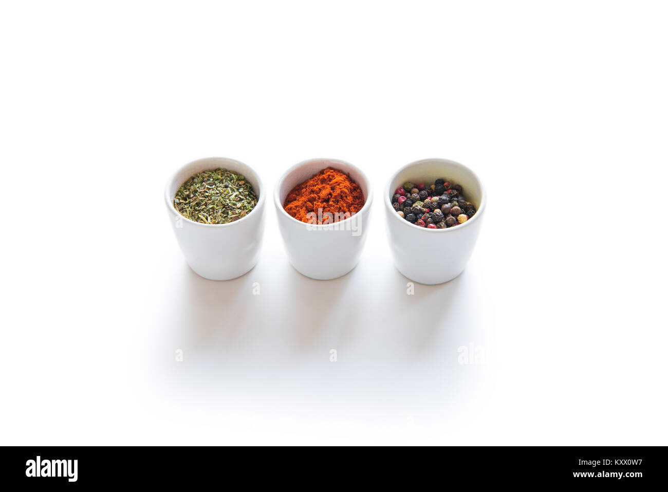 Vista ravvicinata di un assortimento di aromatiche spezie secche in ciotole di ceramica isolata su bianco Foto Stock