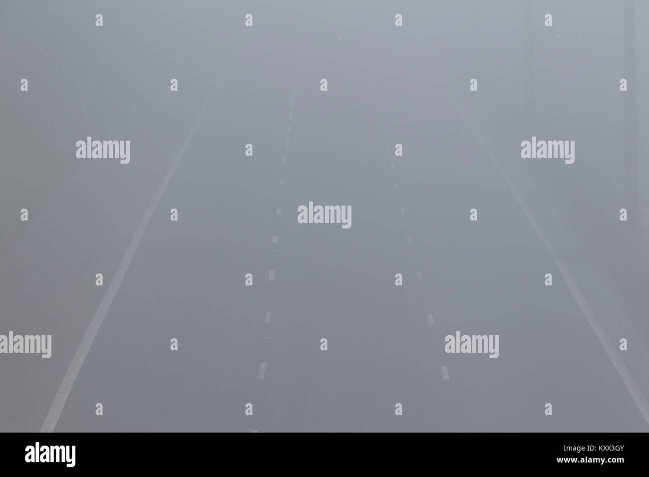 Auto utilizzando la luce fendinebbia in lontananza la guida su autostrada su di un nebbioso giorno nel Regno Unito Foto Stock