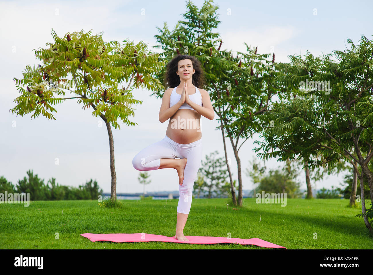 Giovane donna incinta fare yoga all'aperto Foto Stock