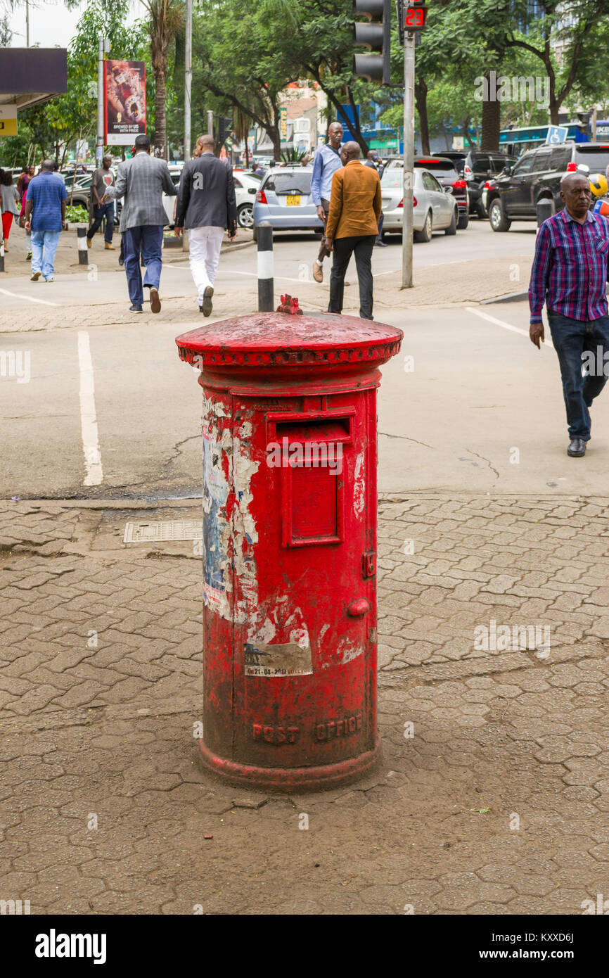 Un vecchio rosso casella postale sul marciapiede come la gente a piedi passato andando sulla vita quotidiana, Nairobi, Kenya, Africa orientale Foto Stock