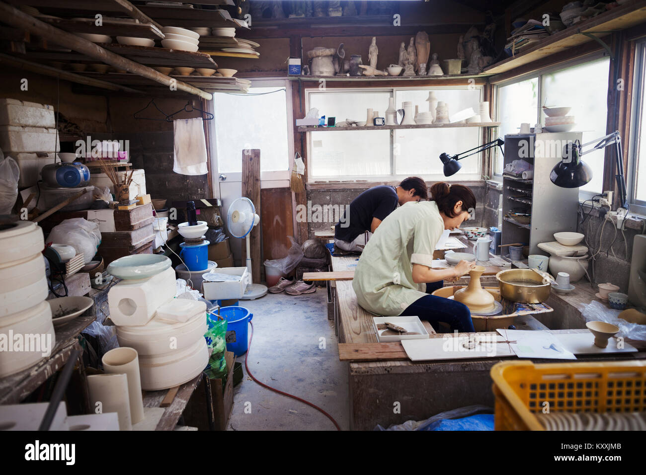 Donna che lavorano in una porcellana giapponese workshop, seduti su un tornio del vasaio, gettando la ciotola. Foto Stock