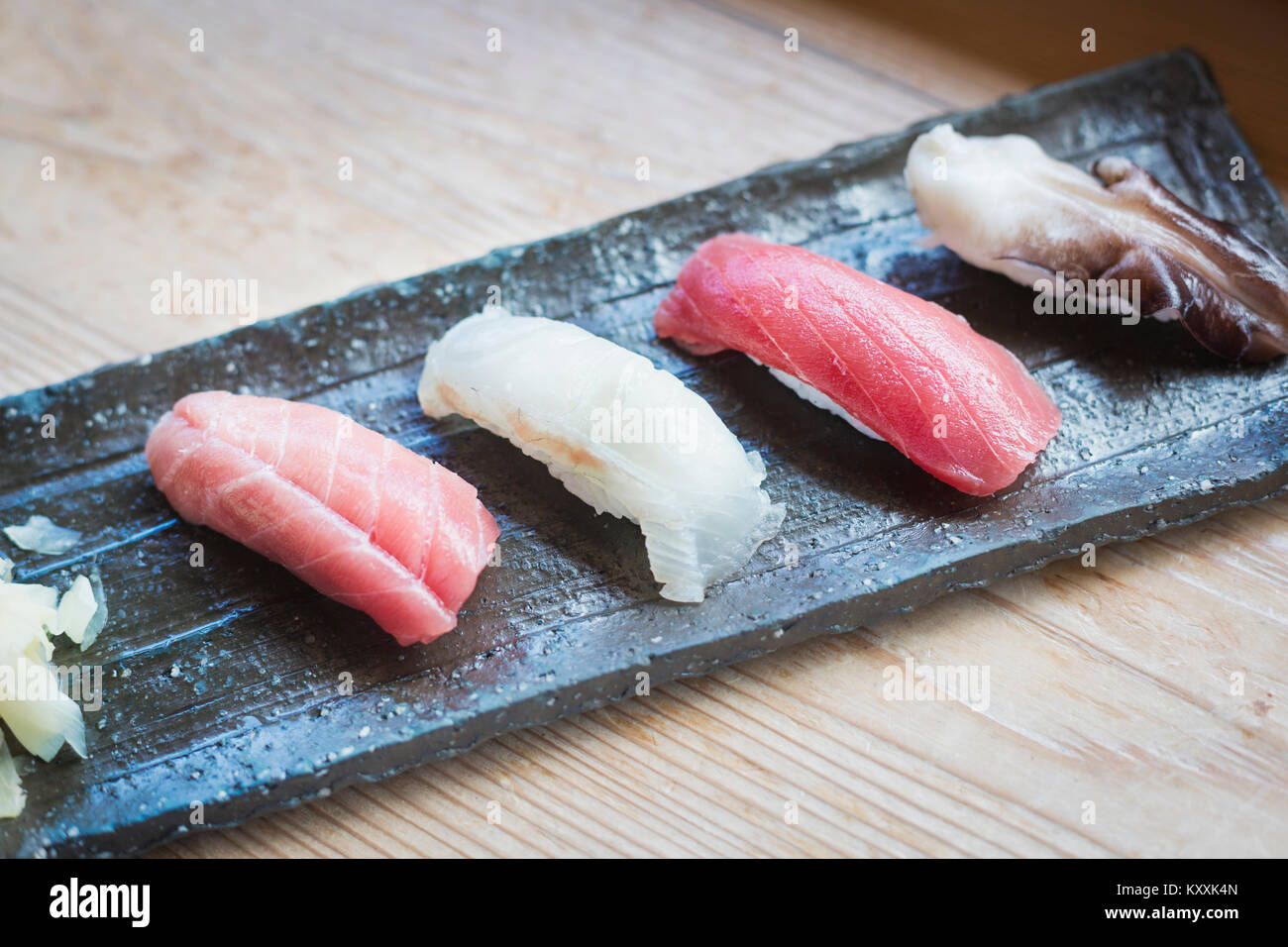 Angolo alto vicino da quattro pezzi di sushi servita su un piatto di forma rettangolare. Foto Stock