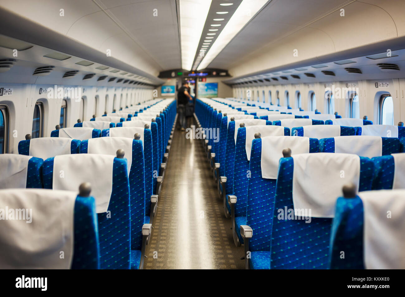 Vista interna del treno passeggeri trasporto con sedili blu, persone in background. Foto Stock