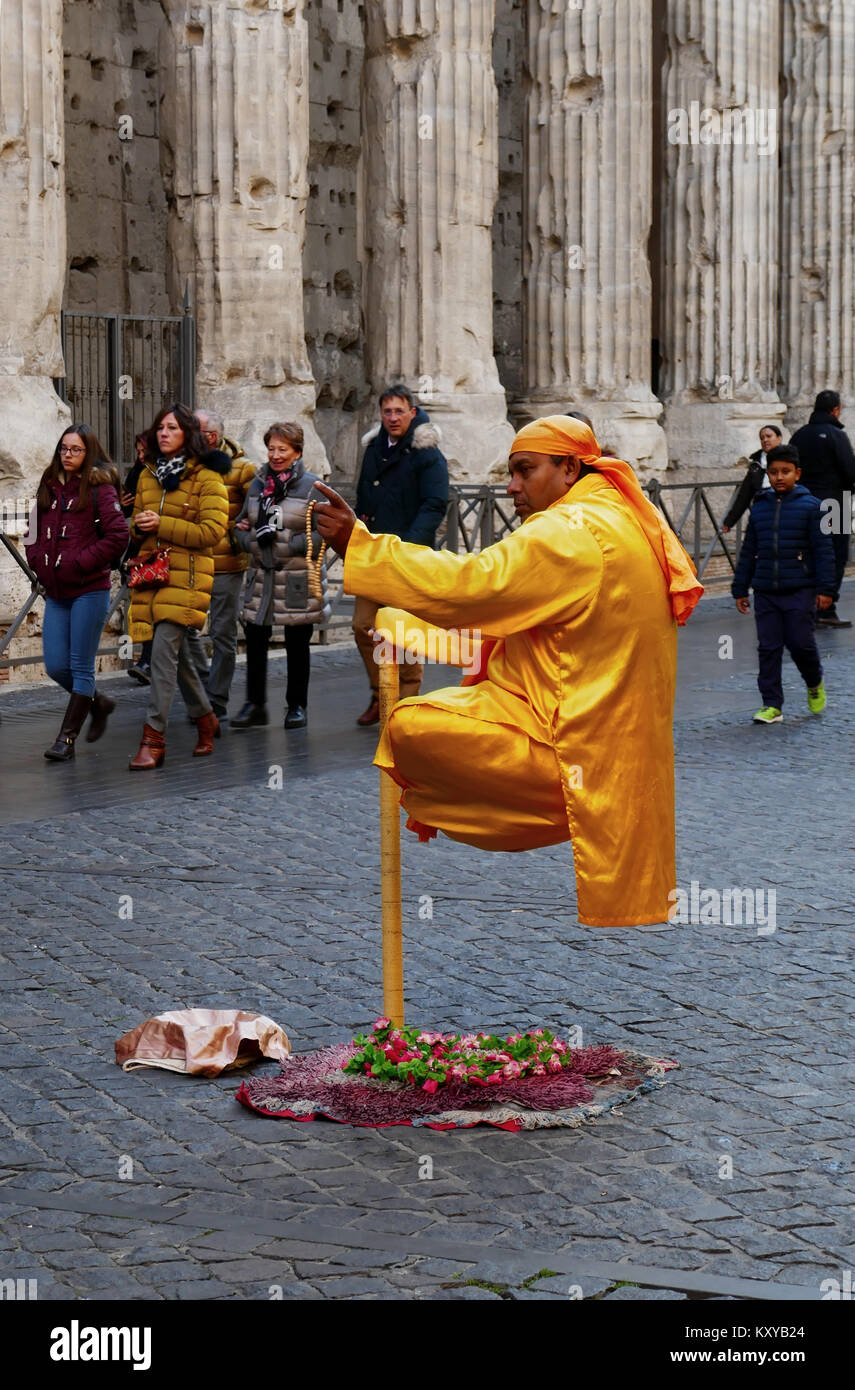 Roma, Italia - 6 dicembre 2017: Street Guru eseguendo la floating uomo illusione con il Tempio di Adriano in background Foto Stock
