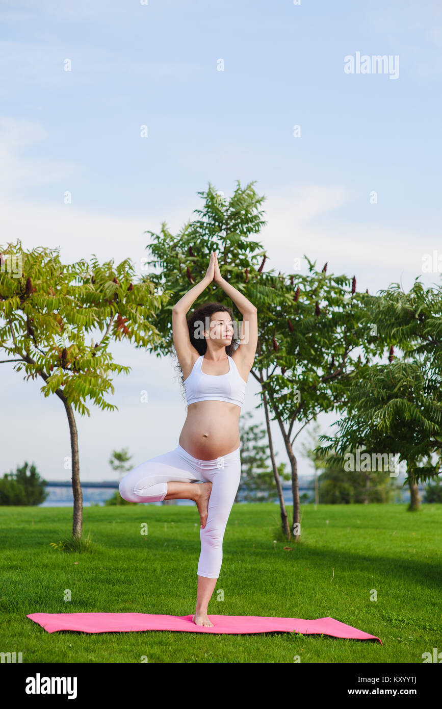 Giovane donna incinta fare yoga all'aperto Foto Stock