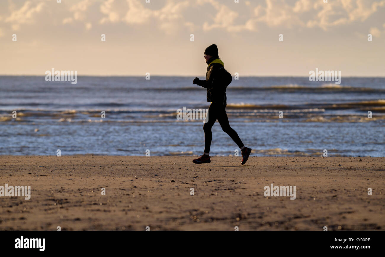 Runner sulla spiaggia di campanatura in inverno il sole. Foto Stock