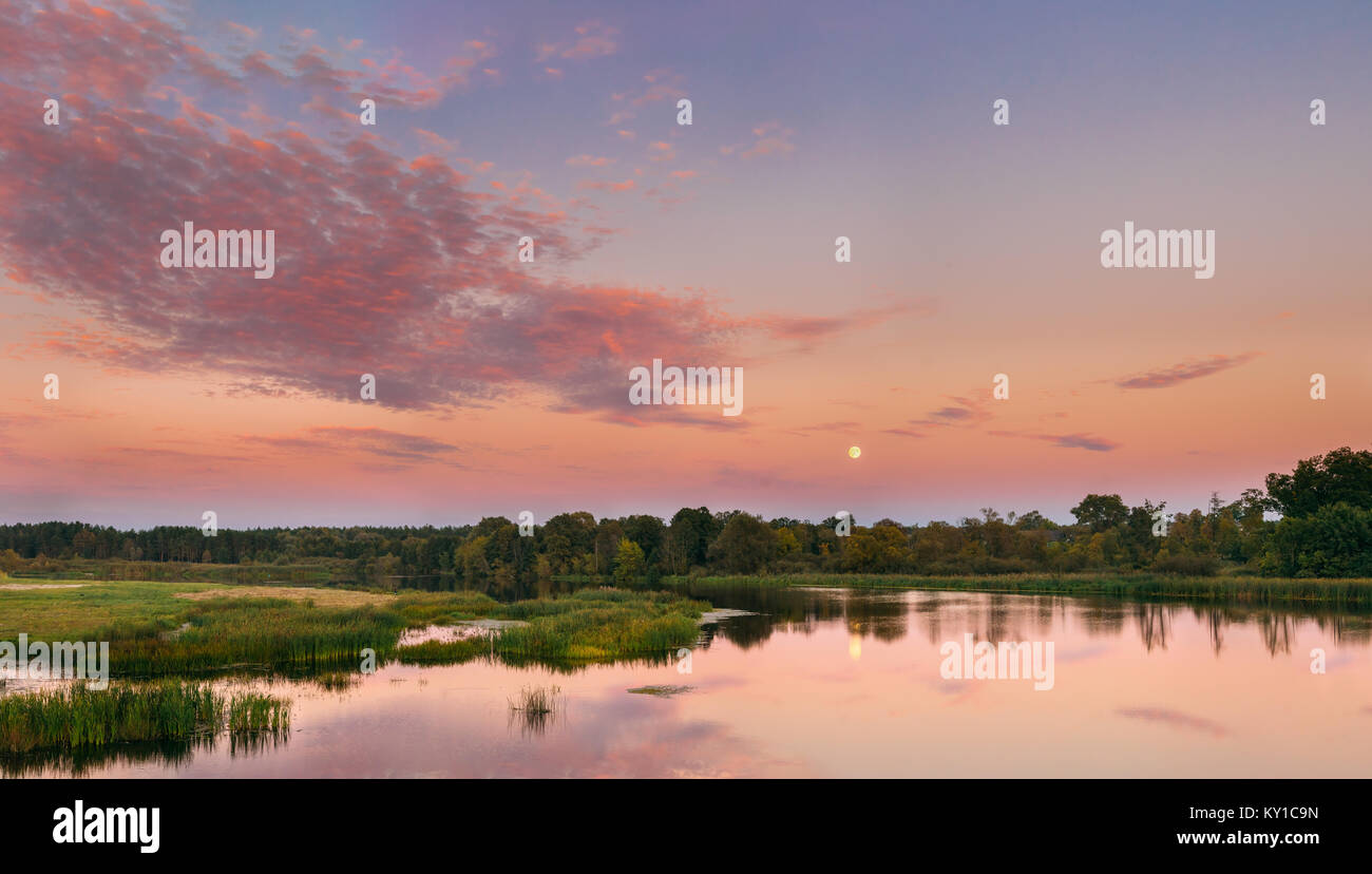 Panorama del paesaggio fluviale in Bielorussia o la parte europea della Russia nel tempo al tramonto di sera d'estate. Luna crescente per l'acqua del lago o fiume. La natura a su Foto Stock