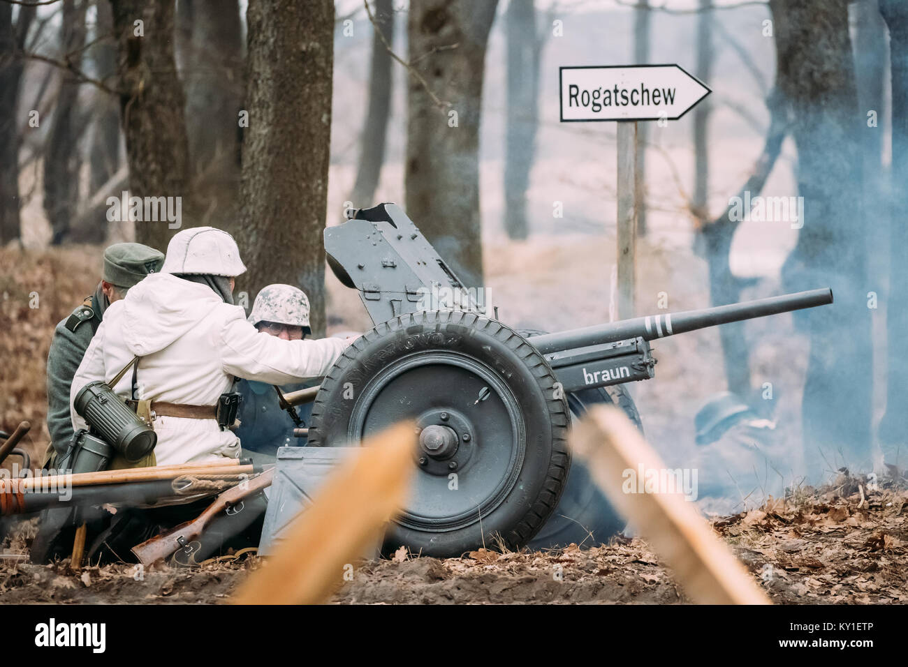 Rogachev, Bielorussia - Febbraio 25, 2017: Re-enactors vestiti come i soldati tedeschi in WWII caricare un cannone gusci in posizione di tiro. Rievocazione storica Foto Stock