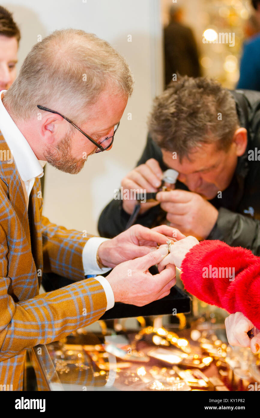 L'arte Antiquariato & interni Fair, Londra, Regno Unito. Un stallholder tenta una corona diamantata sul dito di un browser. Foto Stock