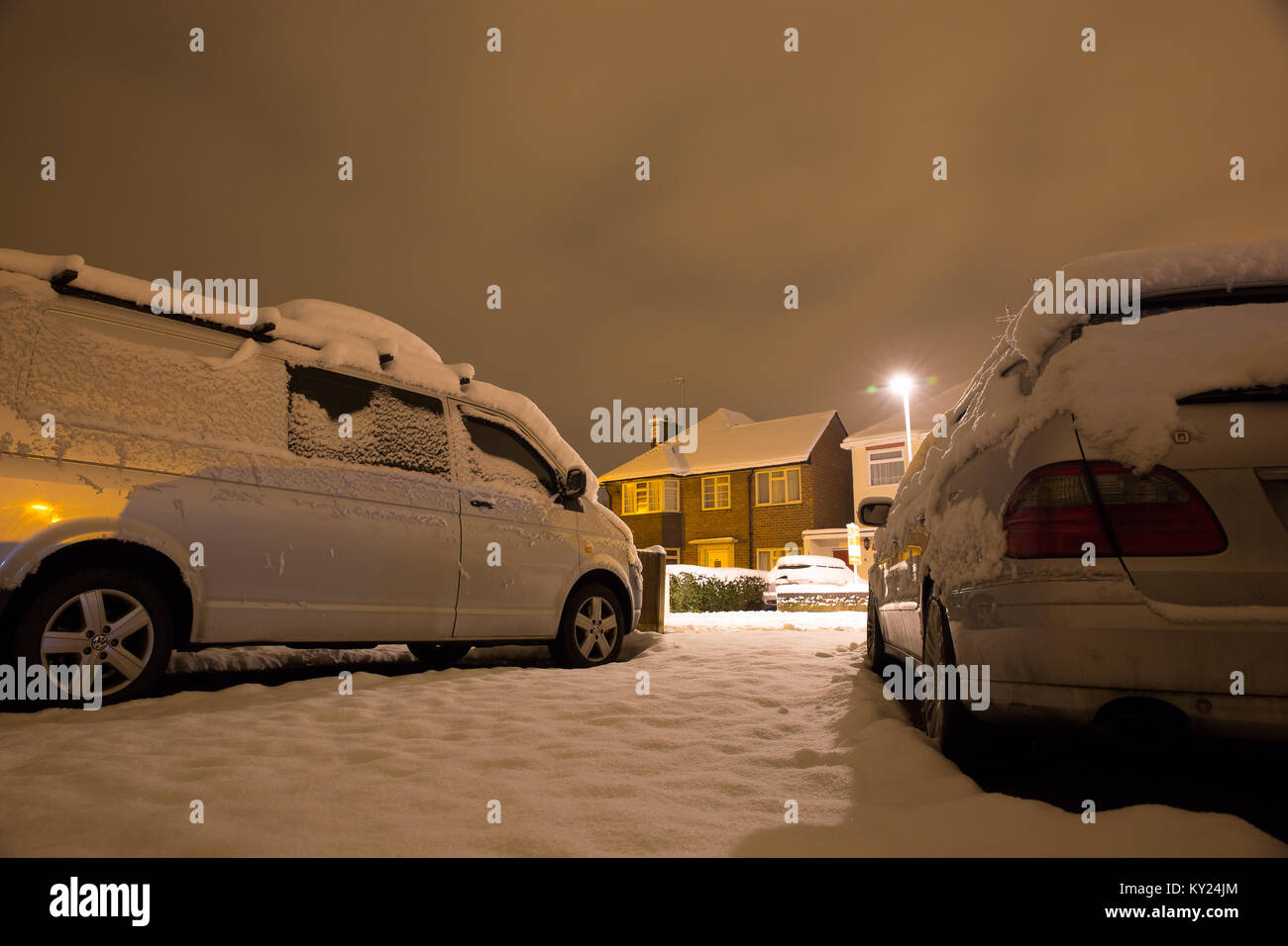 Snowy scena di strada in una fredda sera di dicembre, preso dal viale di accesso di una delle case. Via la luce brilla luminoso. Tutto è calmo e tutto è bianco. Foto Stock