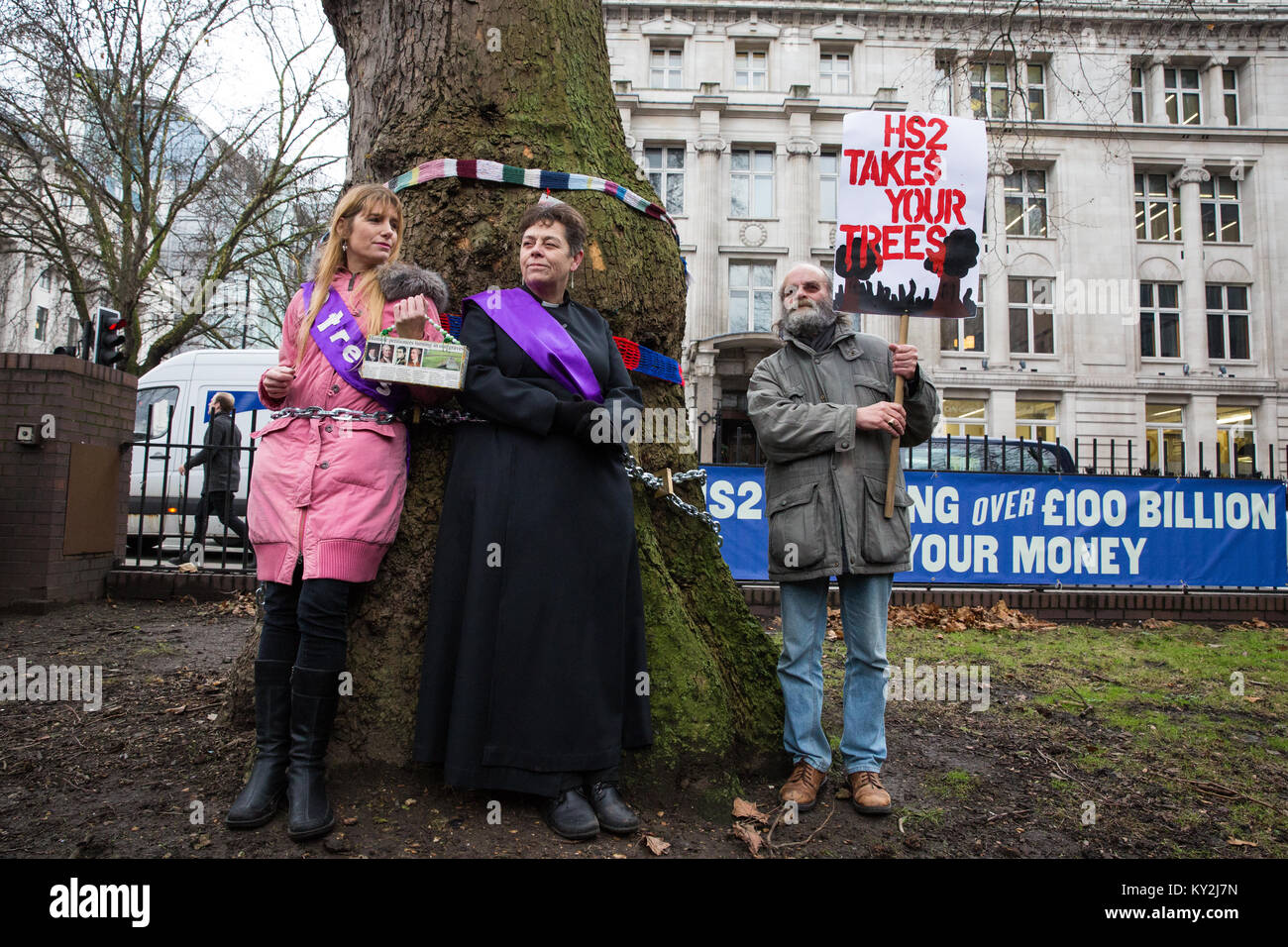 Londra, Regno Unito. 12 gennaio 2018. Anne Stevens, il vicario della chiesa di St Pancras, è incatenata ad un albero con Jo Hurford fuori dalla stazione di Euston come parte di una campagna da parte di residenti locali in protesta contro il progetto di abbattimento di aereo maturo di Londra, Red Oak, Common Lime, Whitebeam comune e Wild Service alberi in Euston Square Gardens per rendere il posto per i siti temporanei per i veicoli da costruzione e un posto di taxi sfollati come parte dei preparativi per la linea ferroviaria HS2. Foto Stock