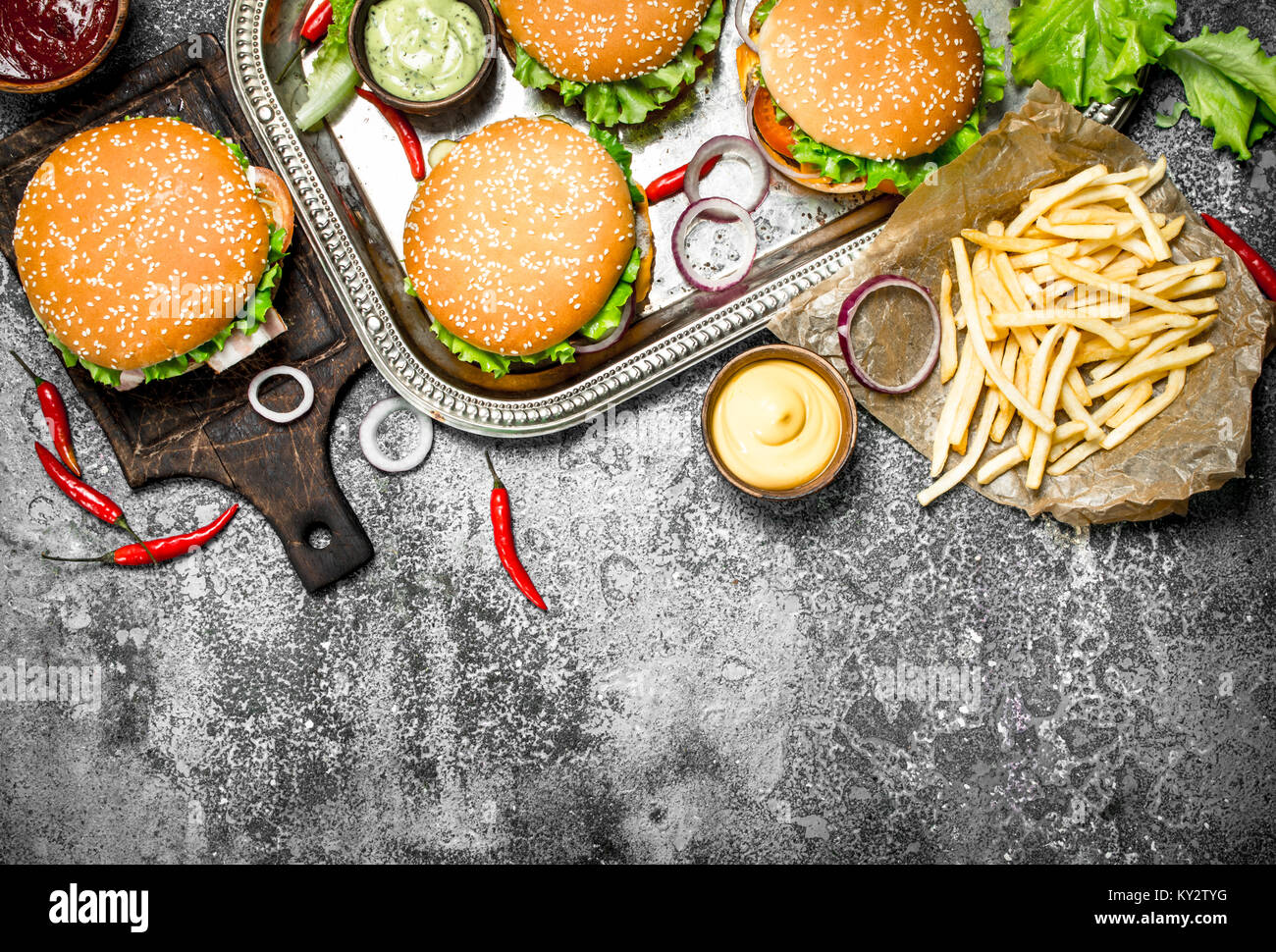 Cucina di strada. Hamburger freschi con verdure e patate fritte. Su uno sfondo rustico. Foto Stock