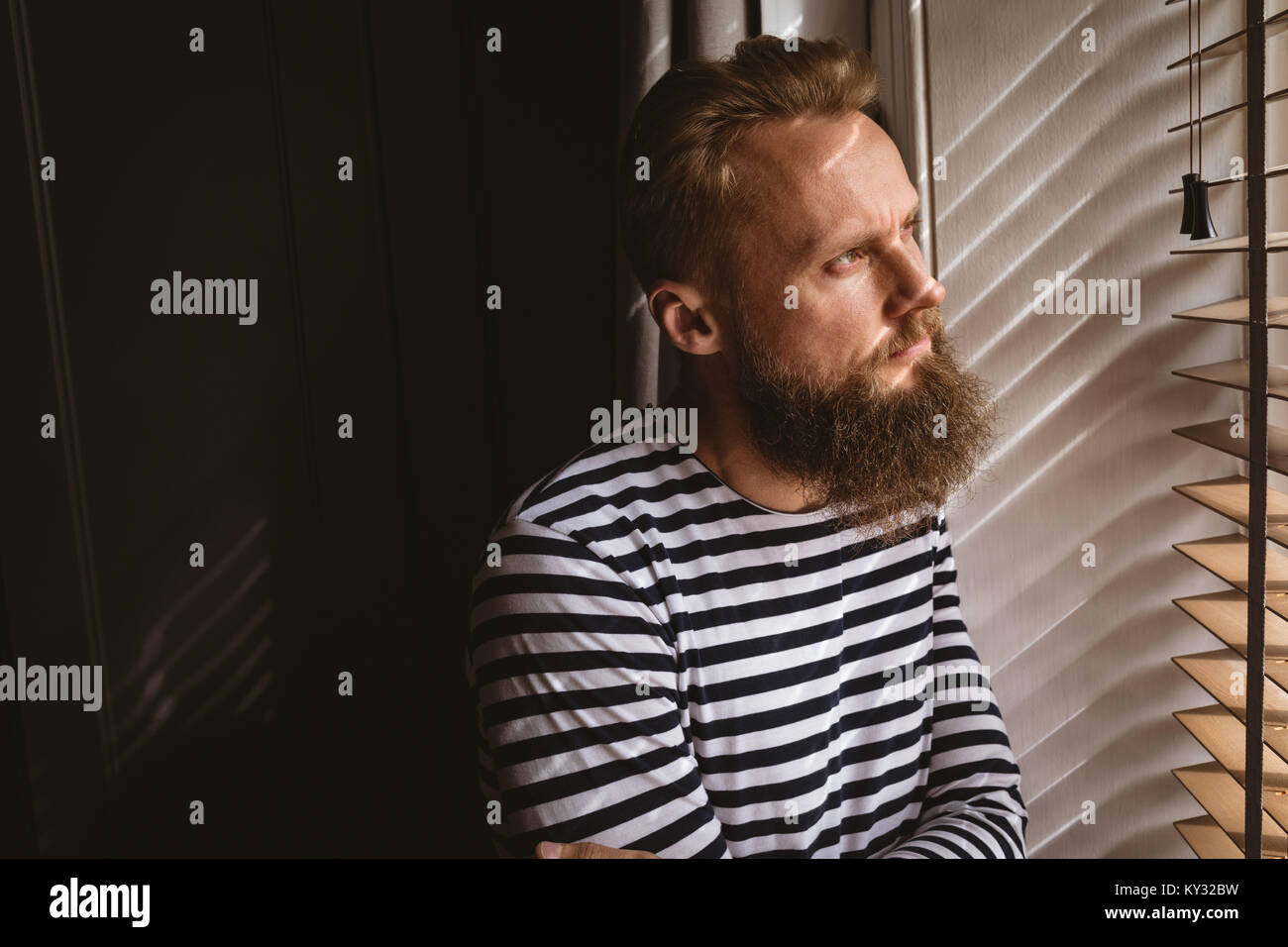 Considerato l'uomo a guardare fuori dalla finestra Foto Stock