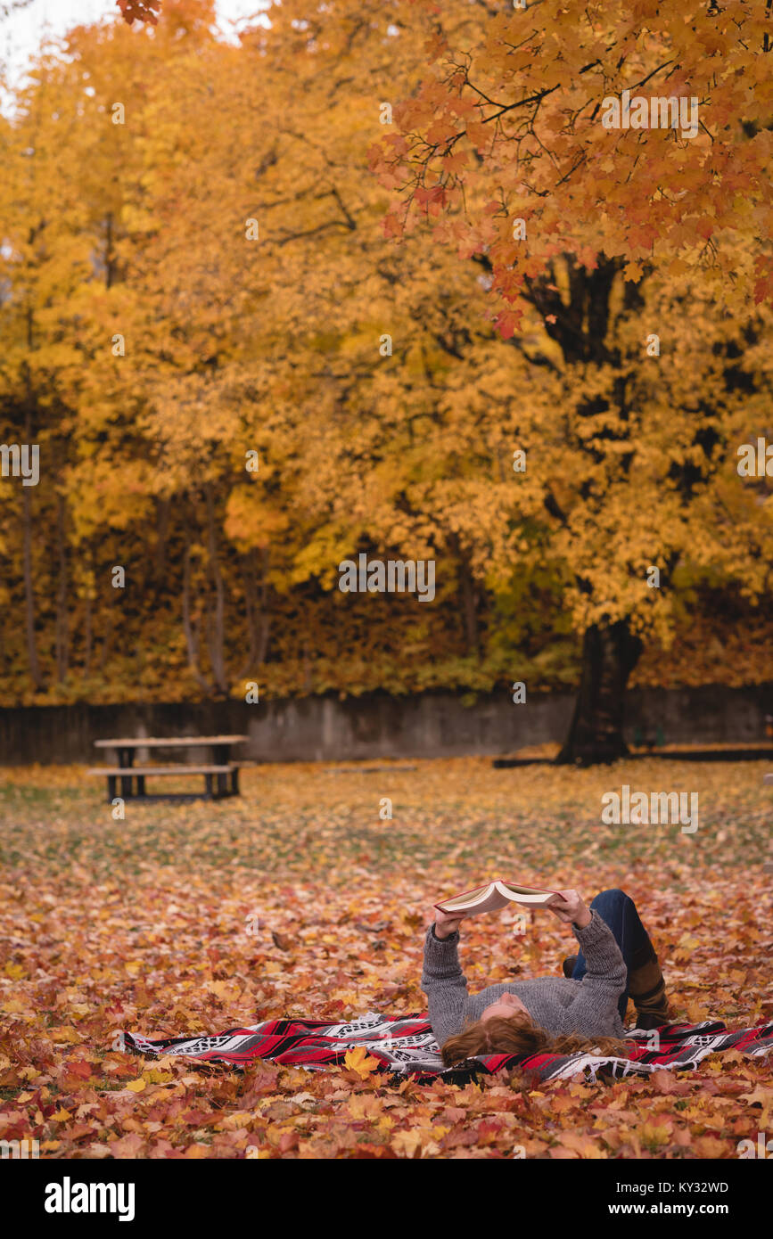 Donna sdraiata nel parco e il romanzo di lettura Foto Stock