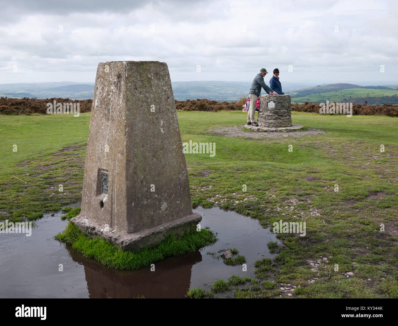 I camminatori con toposcope e trig punto in pole banca, il vertice della lunga Mynd in Shropshire Hills AONB, REGNO UNITO Foto Stock