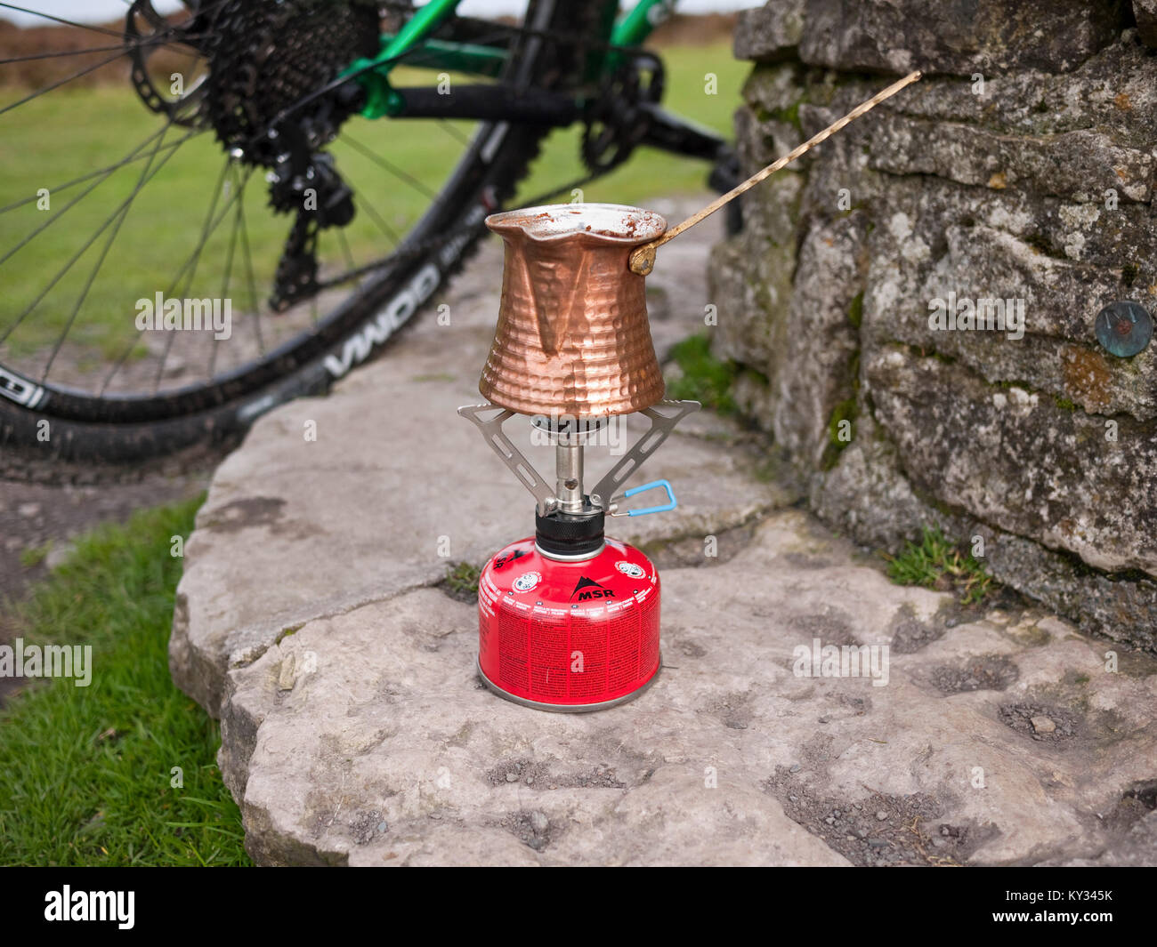 Fare il caffè turco con una tradizionale in rame l ibrik su un gas fornello da campeggio sulla lunga Mynd in Shropshire Hills, REGNO UNITO Foto Stock