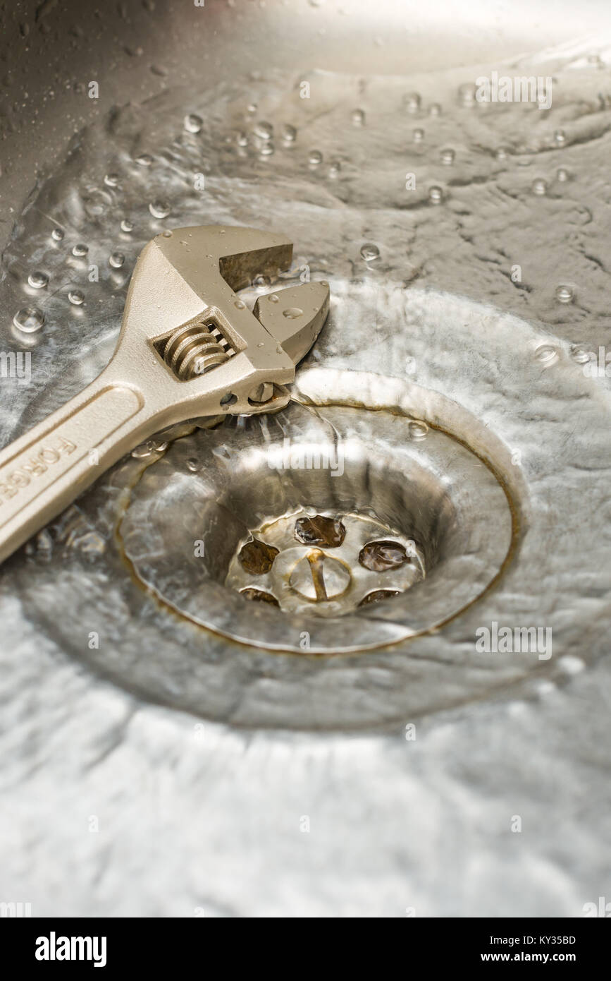 Una chiave appoggiata da un foro di scarico come acqua scorre verso il basso è Foto Stock