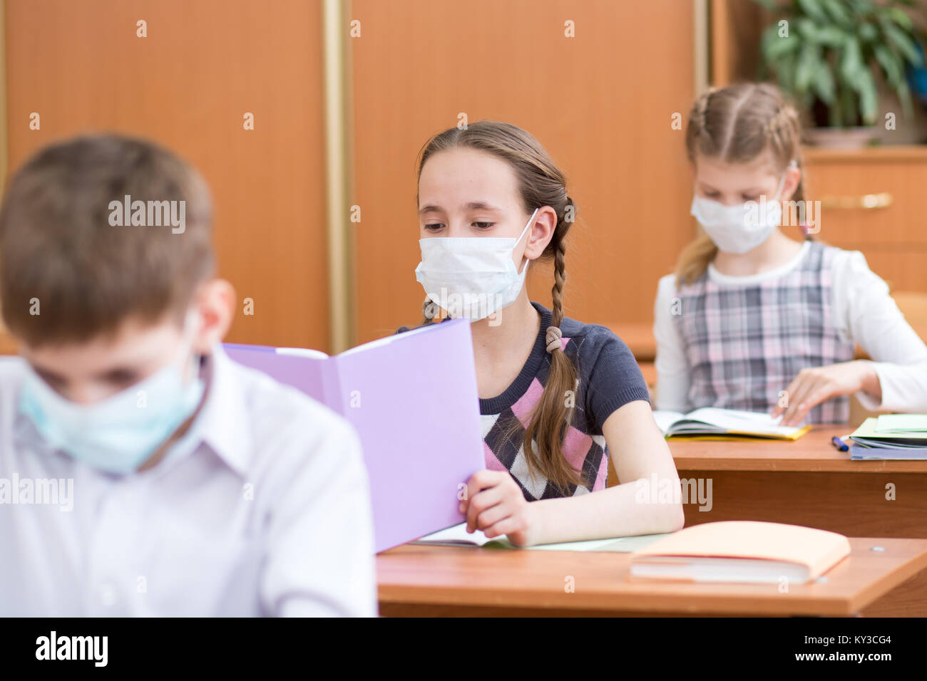 Gli scolari con maschere di protezione contro virus influenzale a lezione in aula Foto Stock