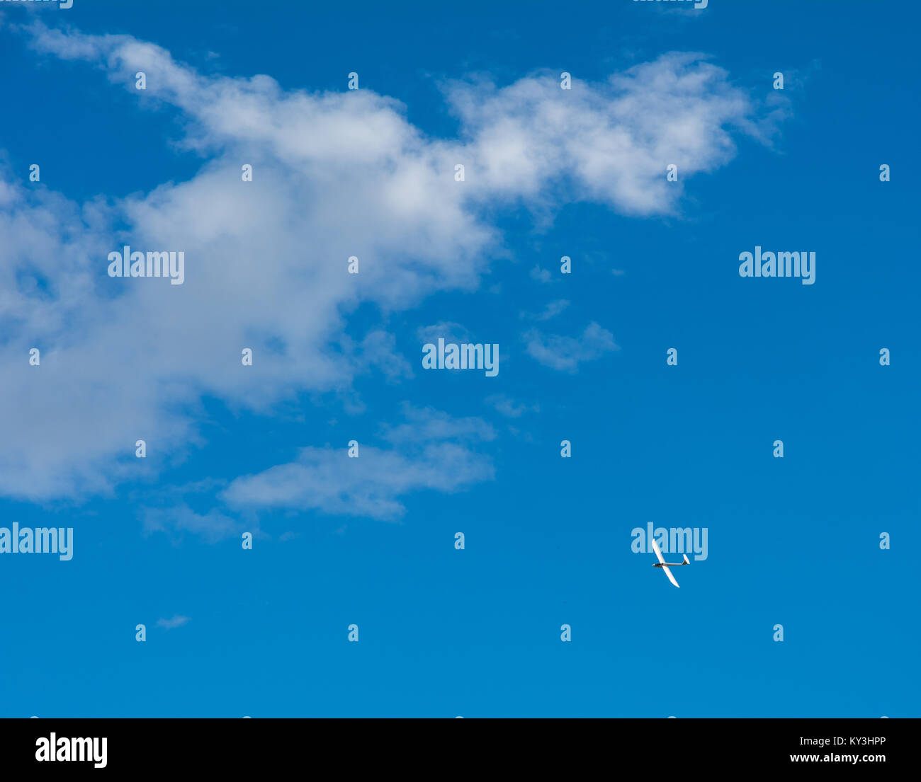 Un parapendio vola nel cielo blu con grandi nuvole bianche. Il parapendio è un piano che non ha il motore Foto Stock