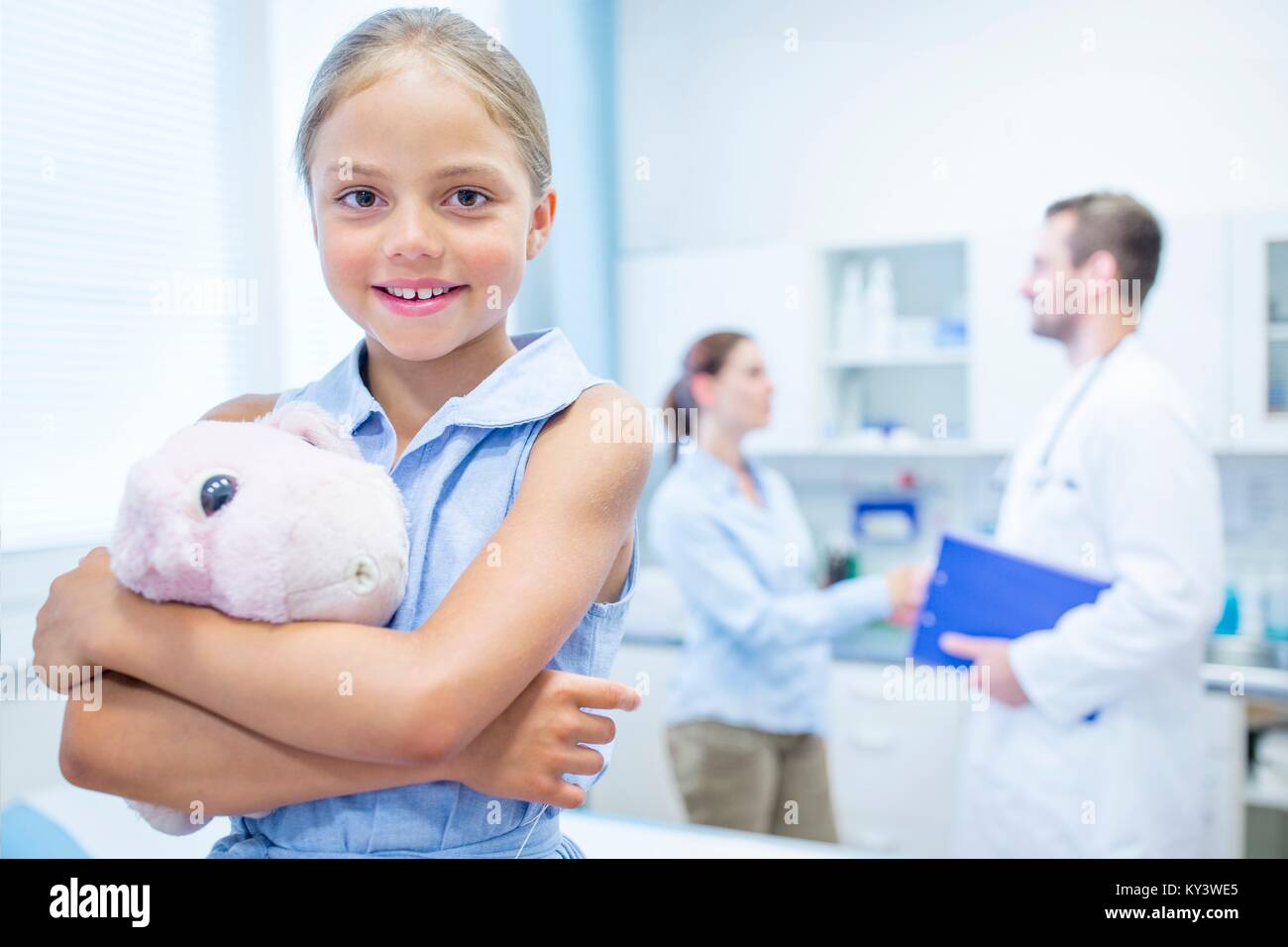 Giovane ragazza in medico abbracciando camera teddy, sorridente. Foto Stock