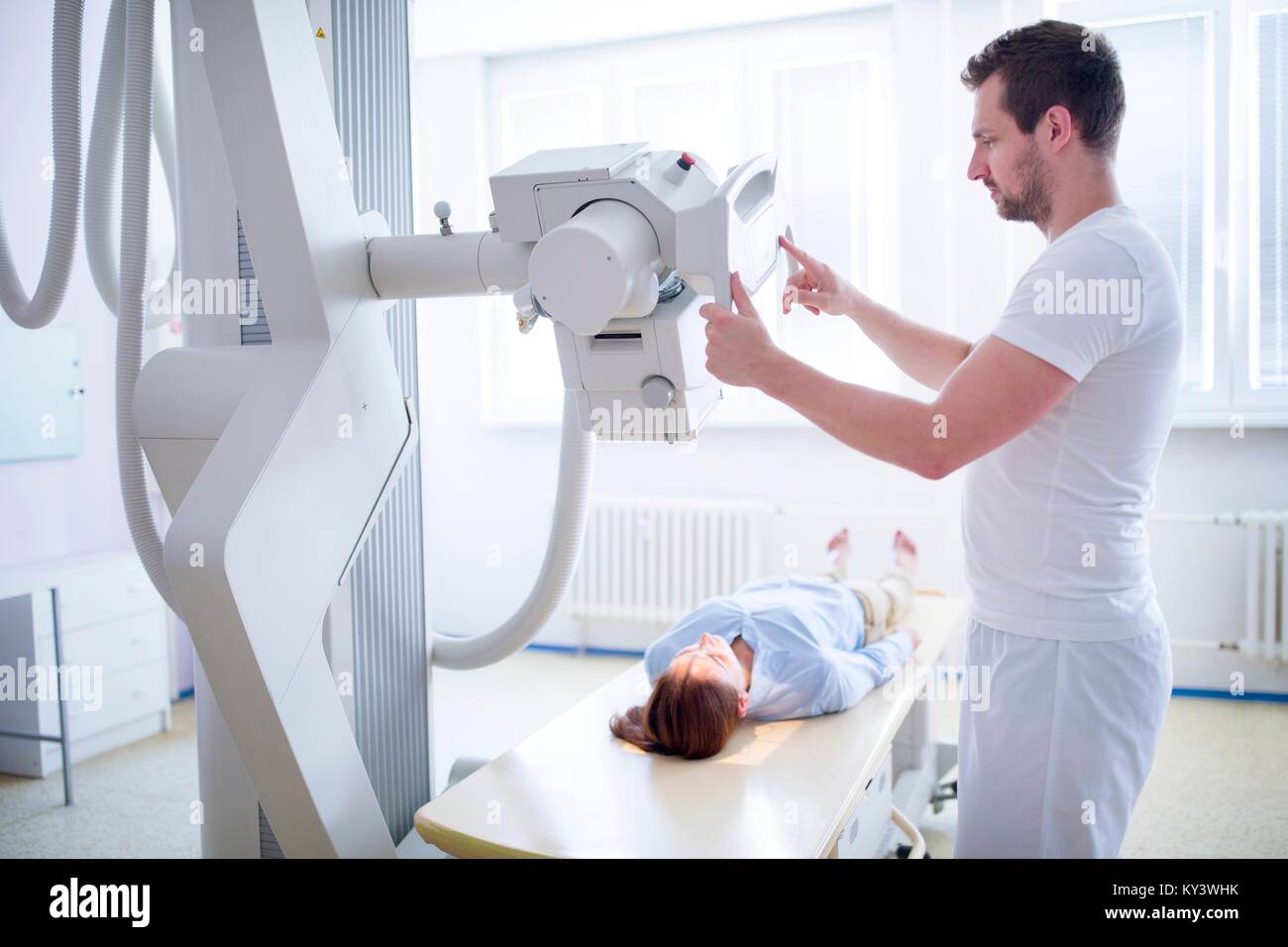 Medico usando una macchina a raggi x femmina con il paziente sdraiato. Foto Stock