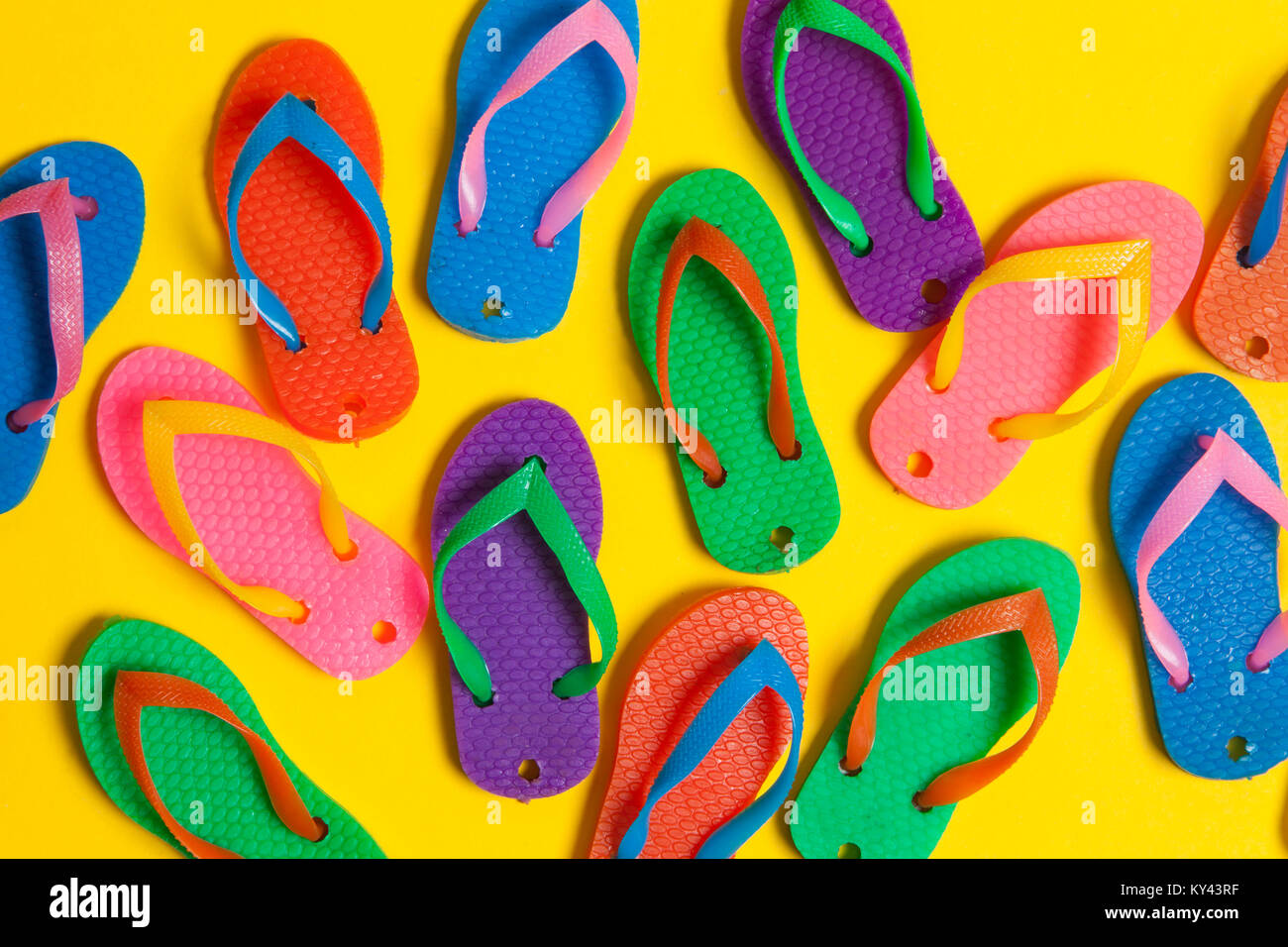 Collezione di coloratissimi estate flip flop sandali su un brillante sfondo giallo Foto Stock